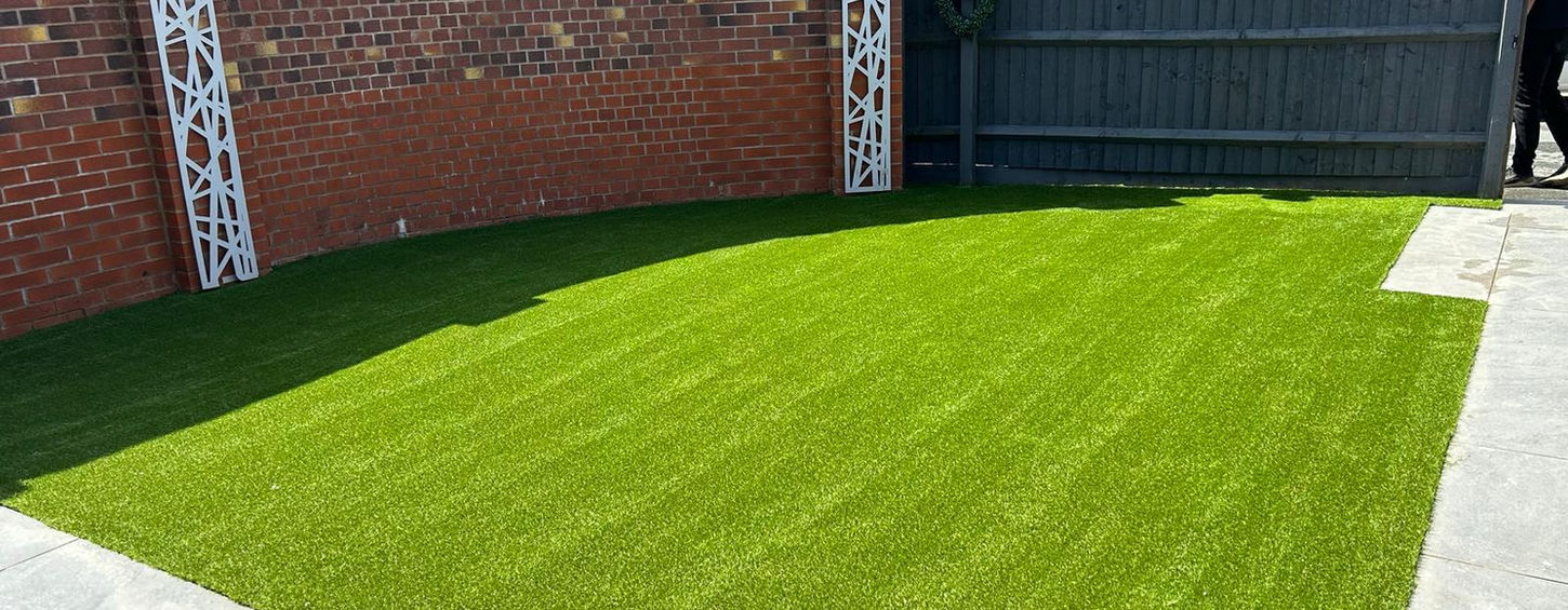 Green lawn in backyard with brick fence and Kt-Landscaping details.