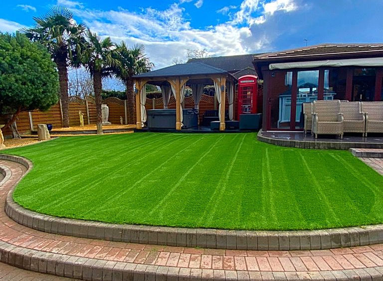 Green lawn with a house in the background and a blue sky above.