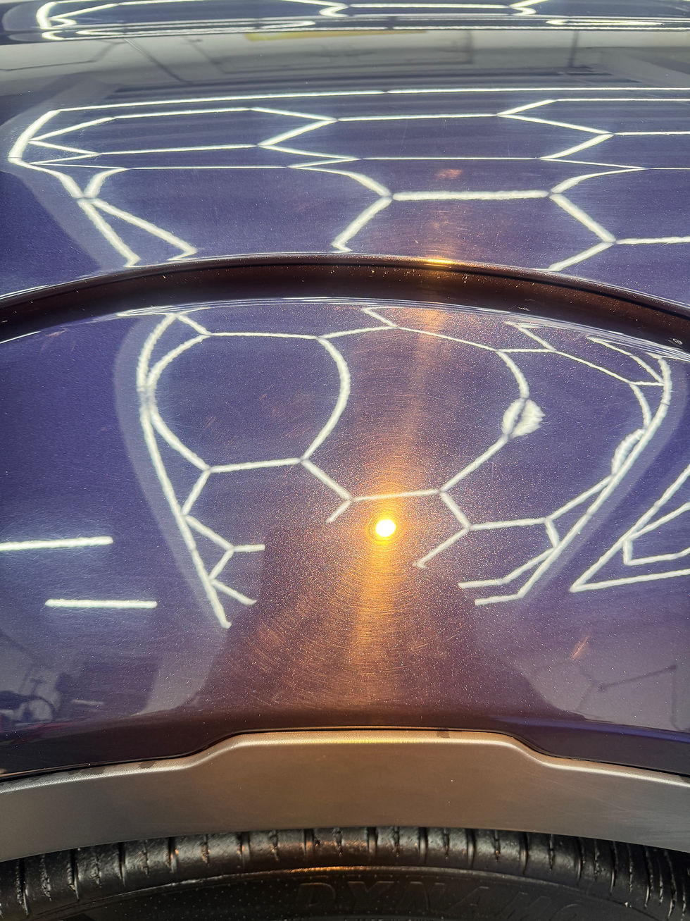 Dark car paint reflecting a bright light and hexagonal pattern