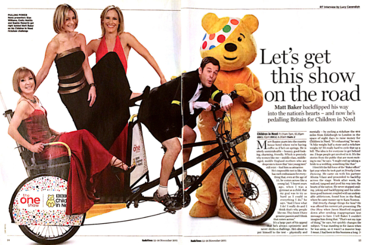 Man on tandem bike in tuxedo with three women in red and black dresses on back, and a person in a yellow bear costume. Text reads, “Let’s get this show on the road.”