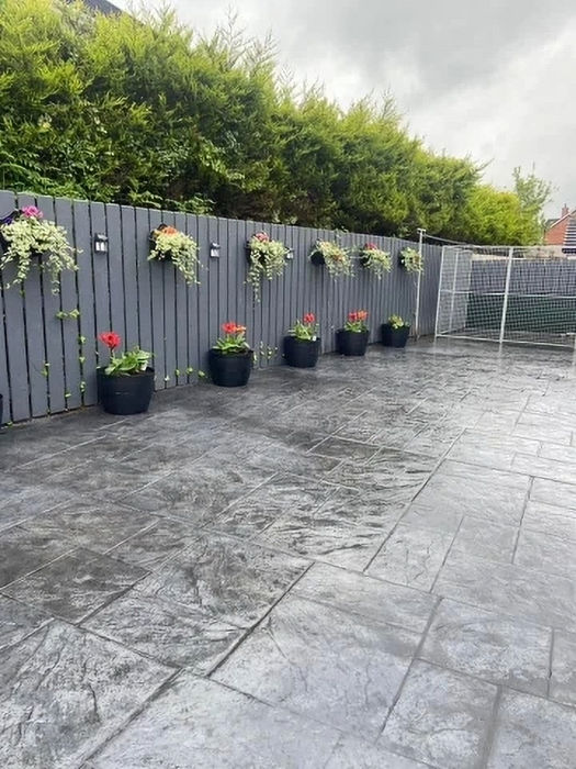 Stamped concrete patio with gray fence and hanging flower baskets