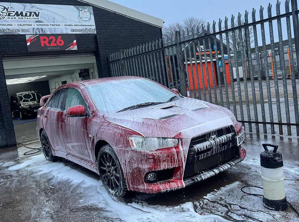 Red car covered in soap suds for a deep clean.