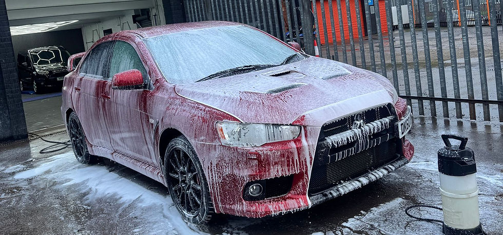 Red car covered in soap suds during a deep clean