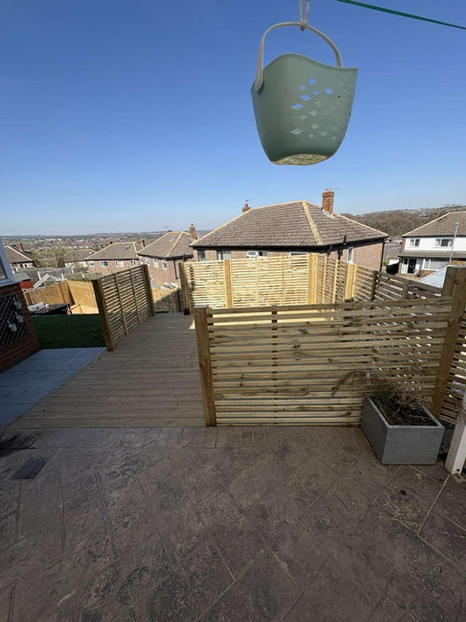 Wooden deck and fence with a green bucket hanging overhead
