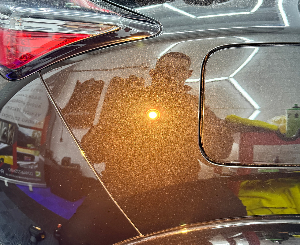 Shiny car surface reflecting a person and lights