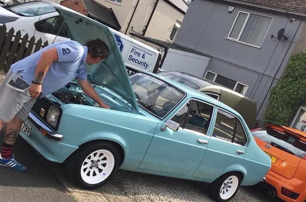 Man inspecting light blue Ford Escort