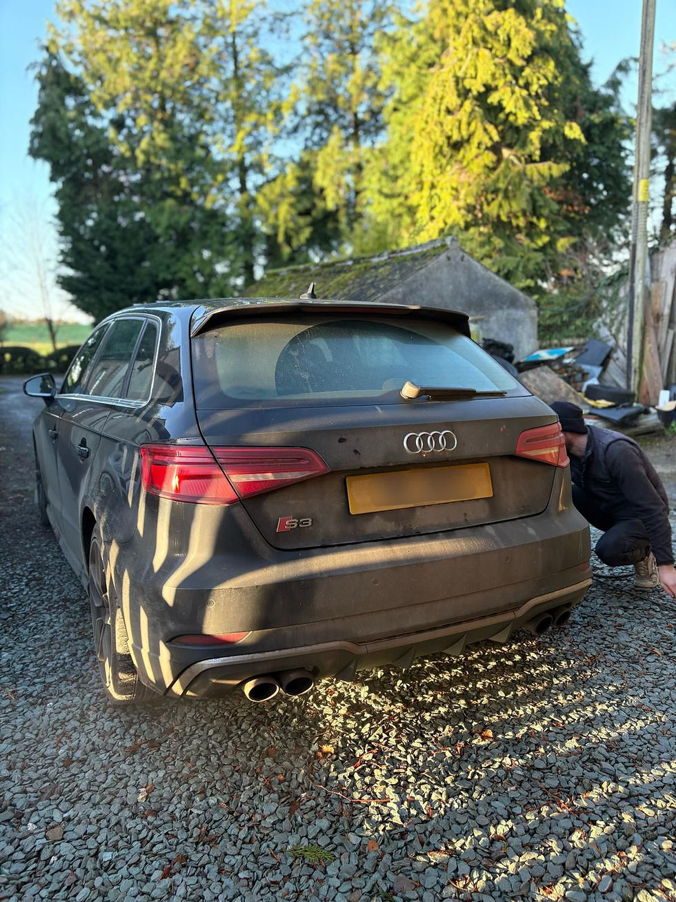 Person cleaning the rear of a dark Audi car
