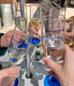 Champagne glasses with McK logo in a cheers position