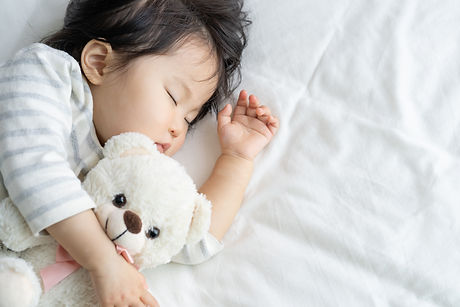 ぬいぐるみを抱いて眠る赤ちゃん