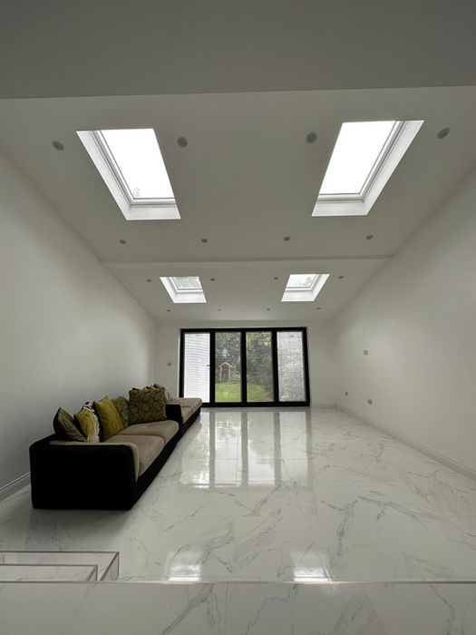 Bright modern house extension in Stanmore featuring skylights, marble-effect tiled flooring, and bi-fold doors leading to the garden, by UKSmartBuild.