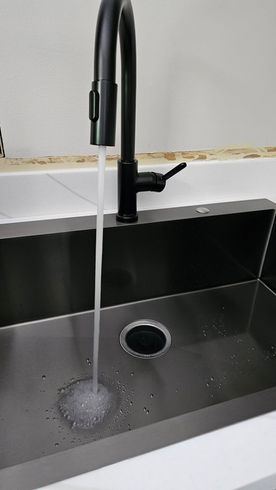Black gooseneck faucet running water into stainless steel sink