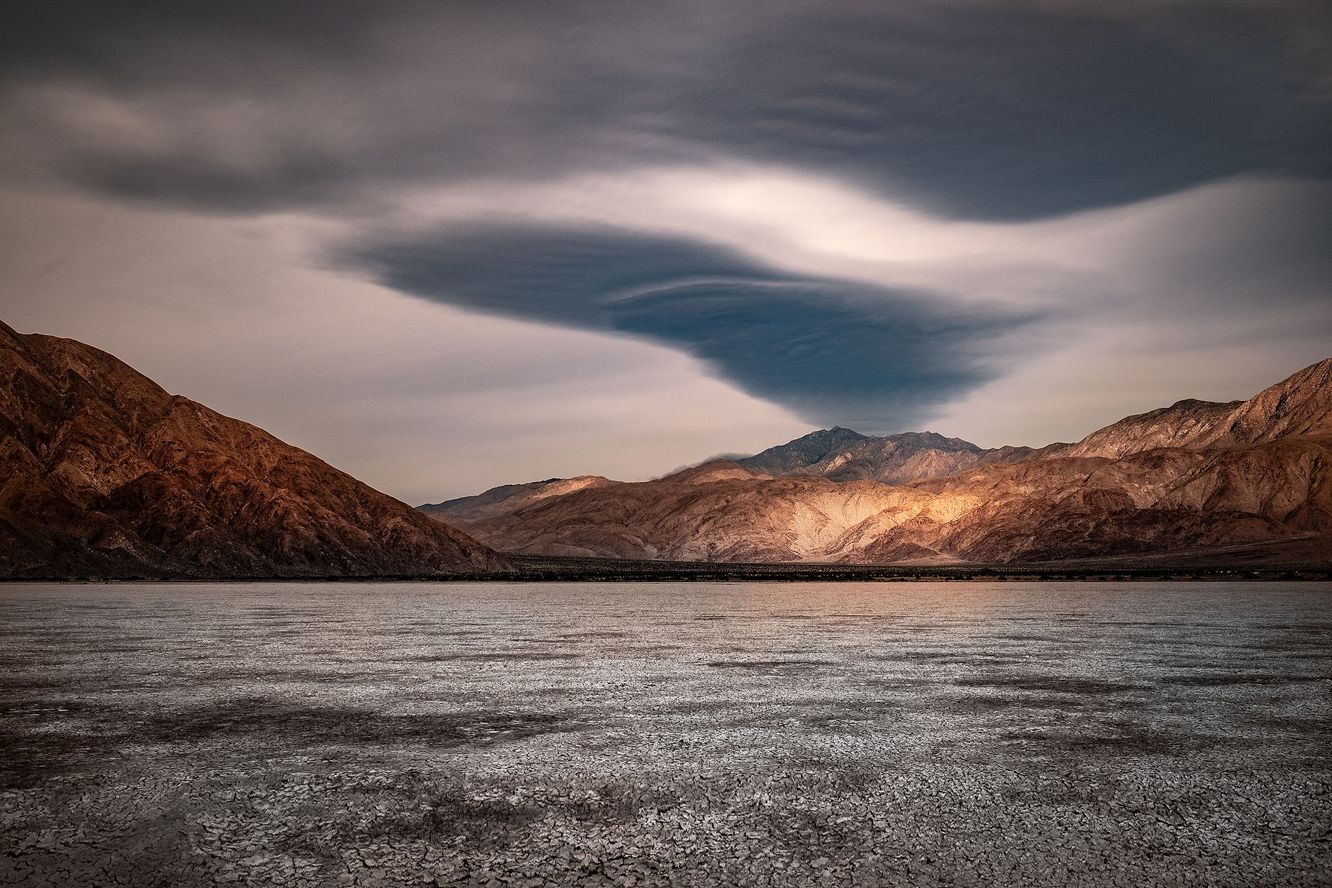 Spot of sunlight illuminates foothills while storm clouds form over Toro Peak in the California desert