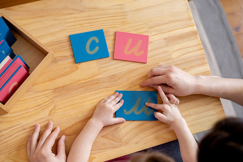 Montessori material. Mom helps her daughter learn letters using the rough alphabet. Child
