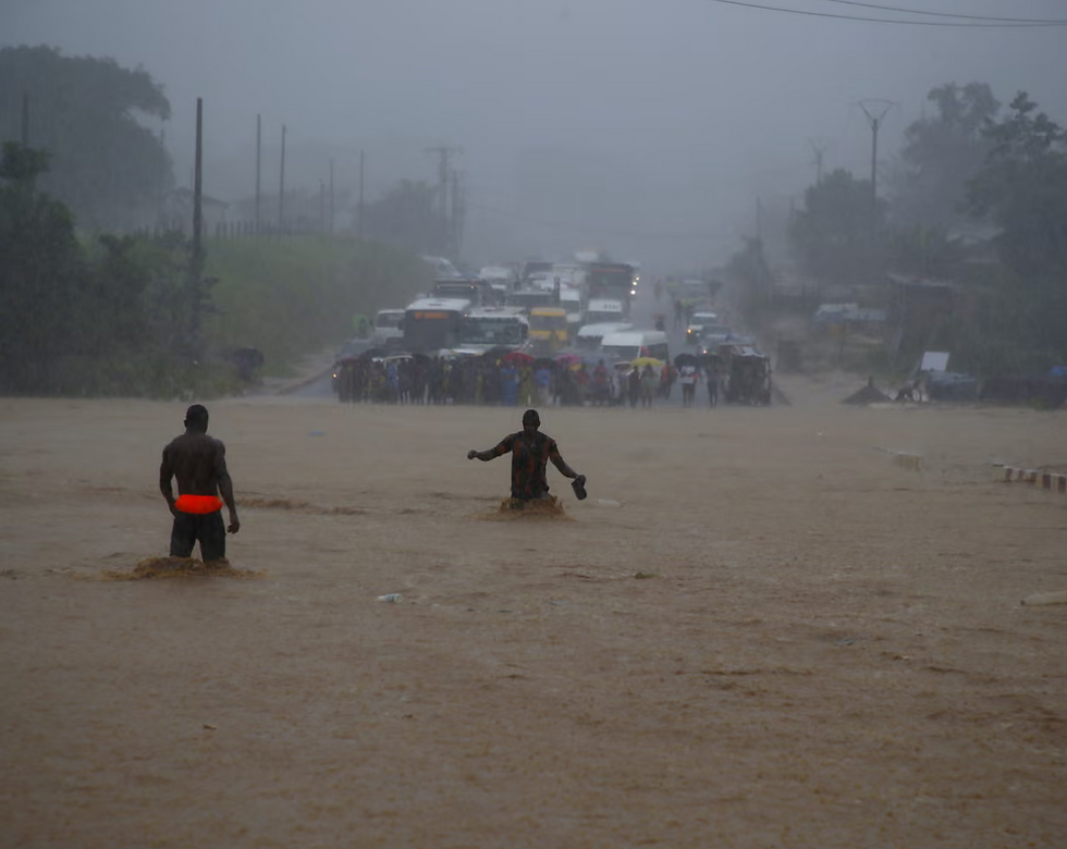 People wade across a flooded road as traffic is halted by torrential rains in Côte d’Ivoire on 25 June. File Photo: Legnan Koula/EPA