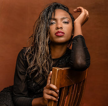 Woman in chair wearing a black dress posing for a portrait in Charleston SC