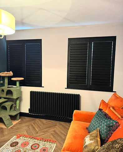 a set of two black plantation shutters on living room windows