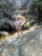 Natalija standing at the petroglyph pool site in St. John surrounded by cliffs and jungle