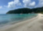 View of Cane Garden Bay in Tortola, British Virgin Islands, with turquoise water, yachts anchored, and green hills in background