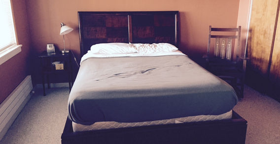 A very dark wood sleigh bed with a checkerboard like pattern on the headboard.