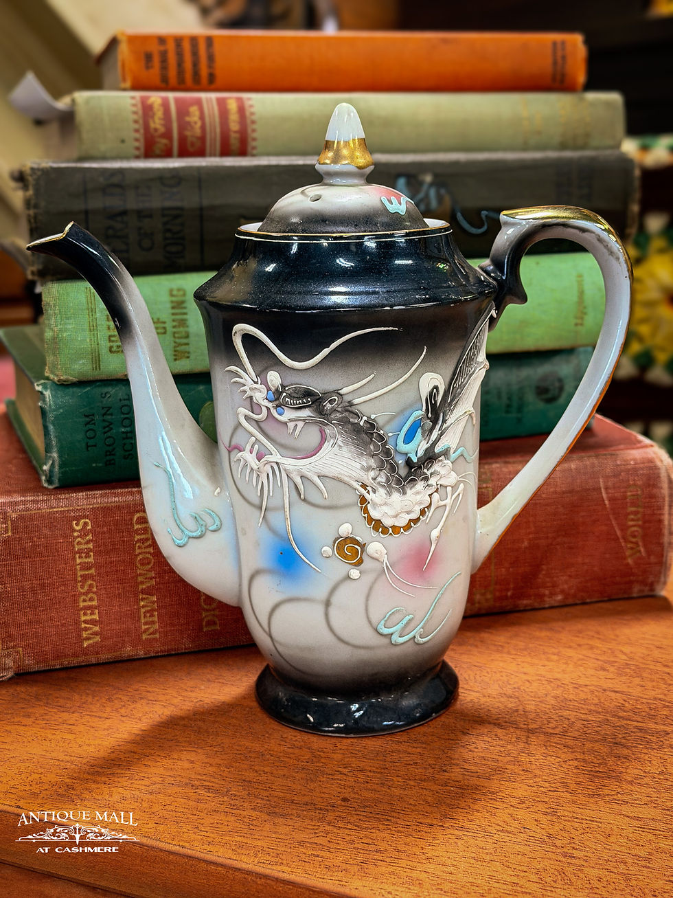 A black, gray, blue, white, and pink teapot with dragon depiction.