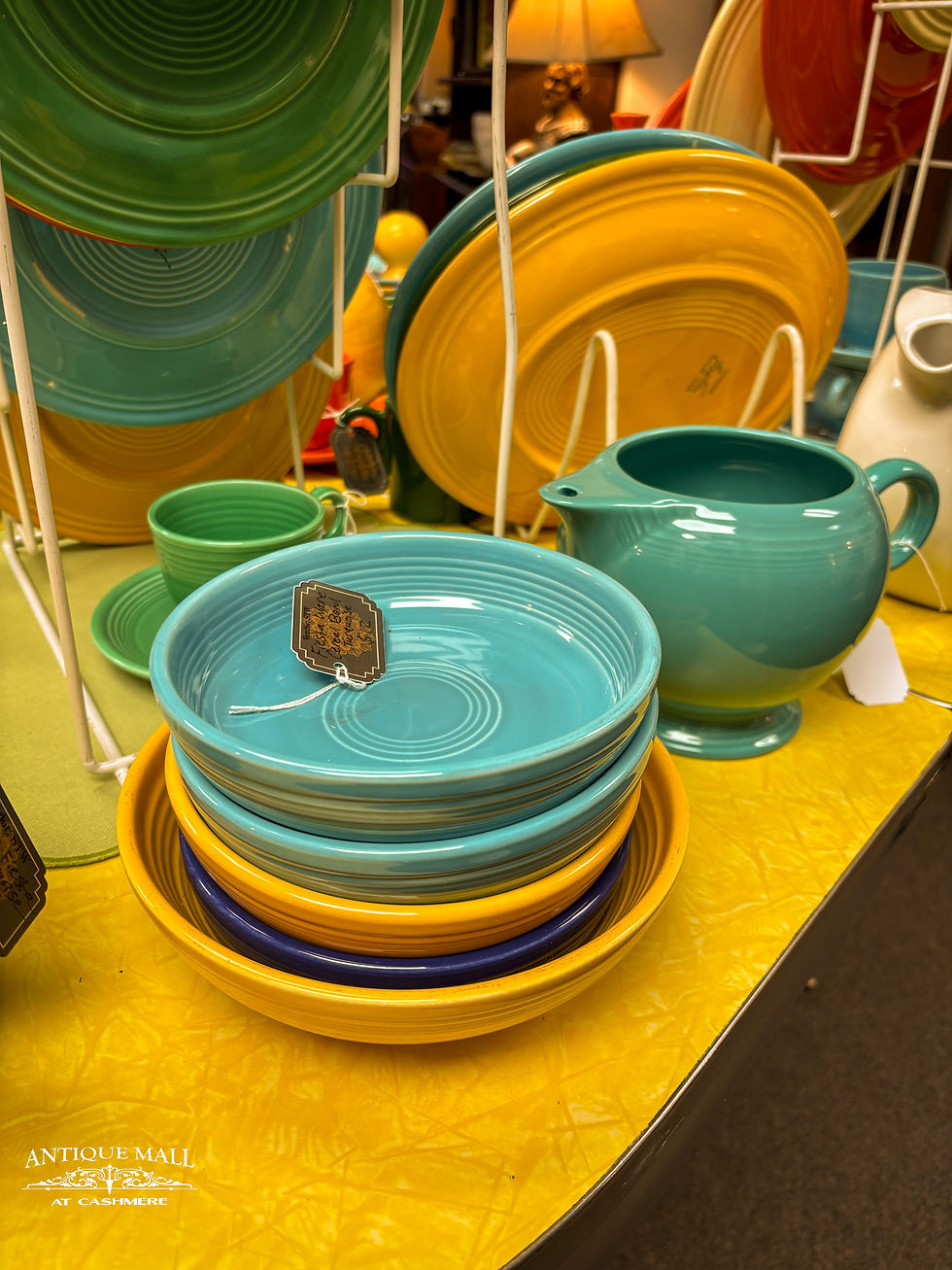Fiesta Ware bowls sit on a table near a pitcher.