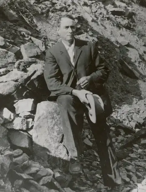 A picture of a man (Ed Pulaski) sitting on a rock on a mountainside.