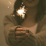 focus photo of a woman holding sparklers