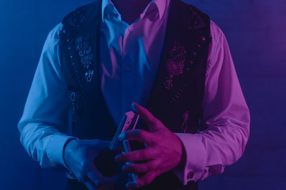 Magicien en tenue de scène manipulant des cartes sous un éclairage bleu et violet, ambiance mystérieuse pour une animation Halloween en entreprise