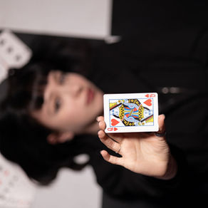 Dame de cœur présentée face à l'objectif sur un damier noir et blanc, visuel d'ambiance pour un spectacle d'hypnose et de mentalisme.