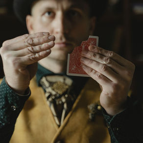 Magicien en gilet jaune présentant une carte à dos rouge en gros plan, en magie de proximité.