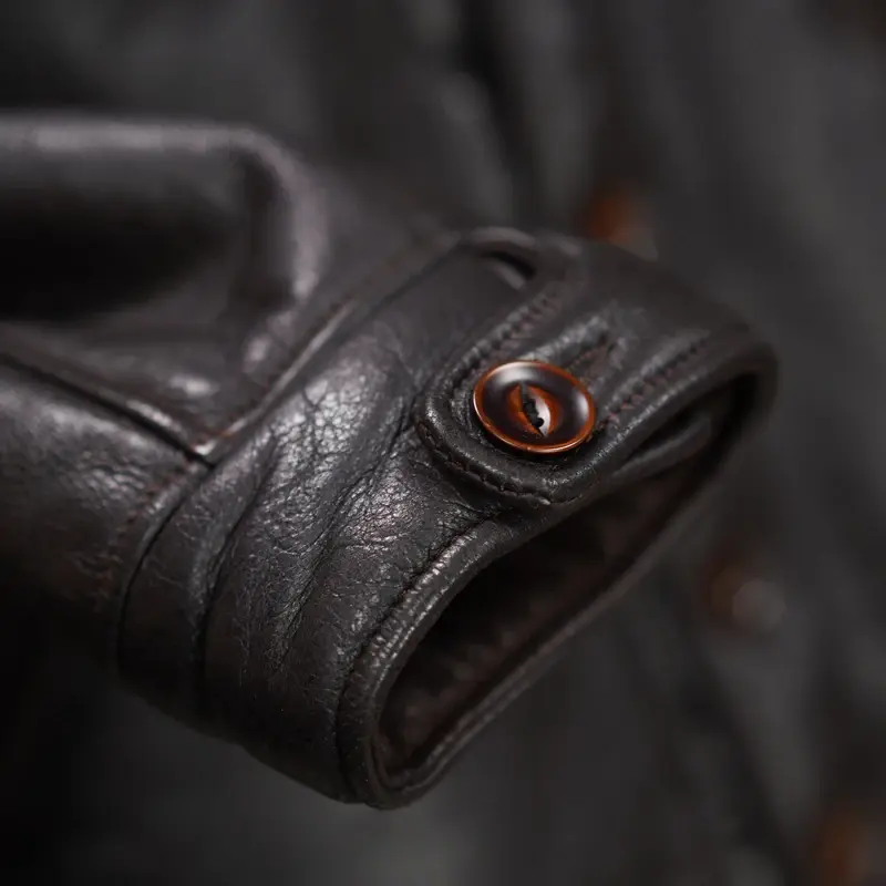 Thumbnail: Dark brown leather jacket with a plush brown collar, buttoned front, and two angled pockets, hanging in a store.
