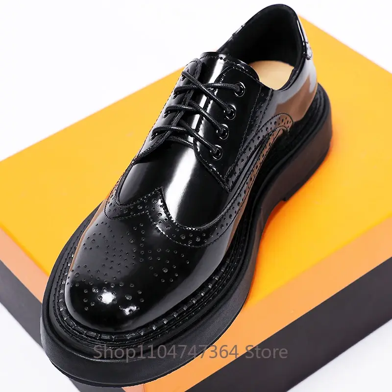Shiny black oxford shoe with brogue detailing on an orange and black box.