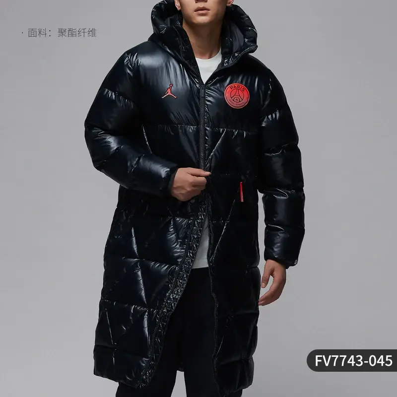 Thumbnail: Man wearing a long, shiny black puffer coat with red logos, hood up, hands adjusting the front zipper.