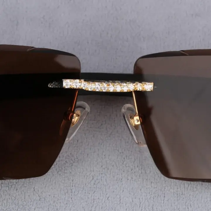 Miniatură: Close-up of sunglasses showing brown lenses, gold accents, and a diamond-studded bridge with clear nose pads.