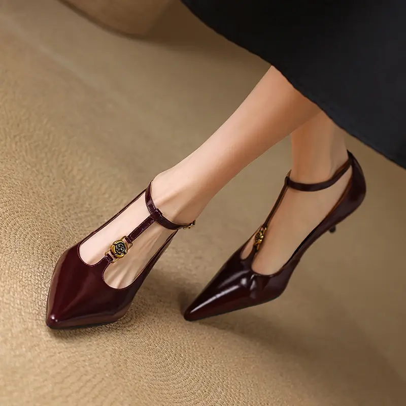 Miniatura: Maroon pointed-toe T-strap heels with gold rose embellishments on a beige carpet background.
