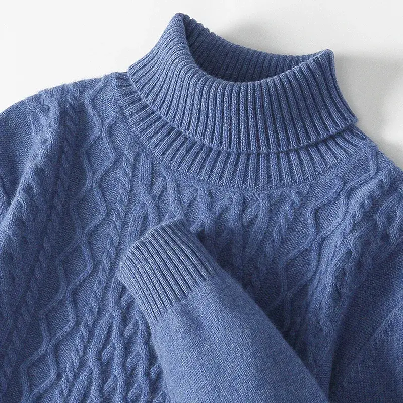 Blue cable-knit turtleneck sweater with ribbed collar and cuffs, featuring a textured pattern.