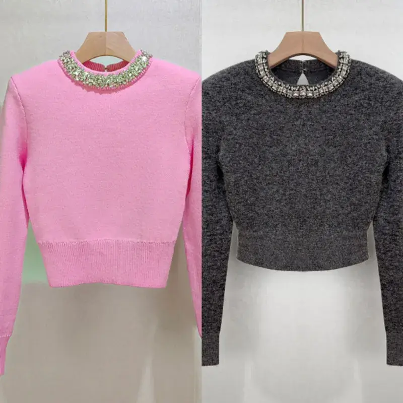 Pink and gray sweaters with beaded collars, displayed on hangers against a neutral background.