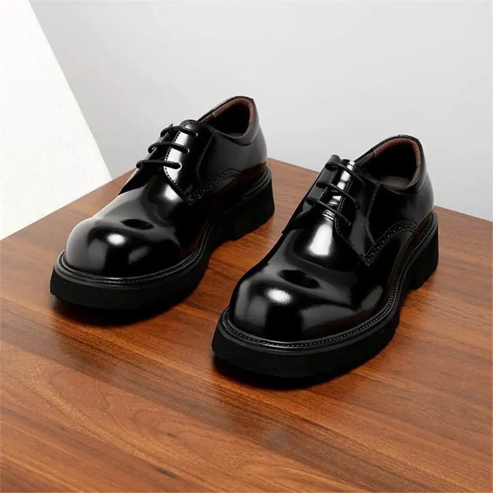 Shiny black leather lace-up shoes with chunky soles on a wooden surface.