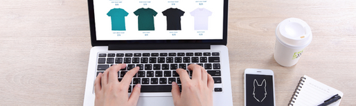 Person typing on a laptop with an eCommerce website on screen, next to a smartphone displaying the GirlDog Digital logo.