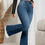 Thumbnail: Woman wearing black top and blue jeans, standing in front of plant
