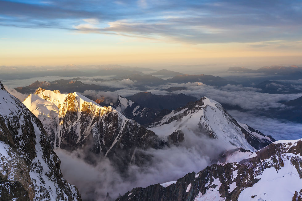 Chaîne de montagnes enneigées au lever du soleil, sommets dorés, mer de nuages sous un ciel pastel.
