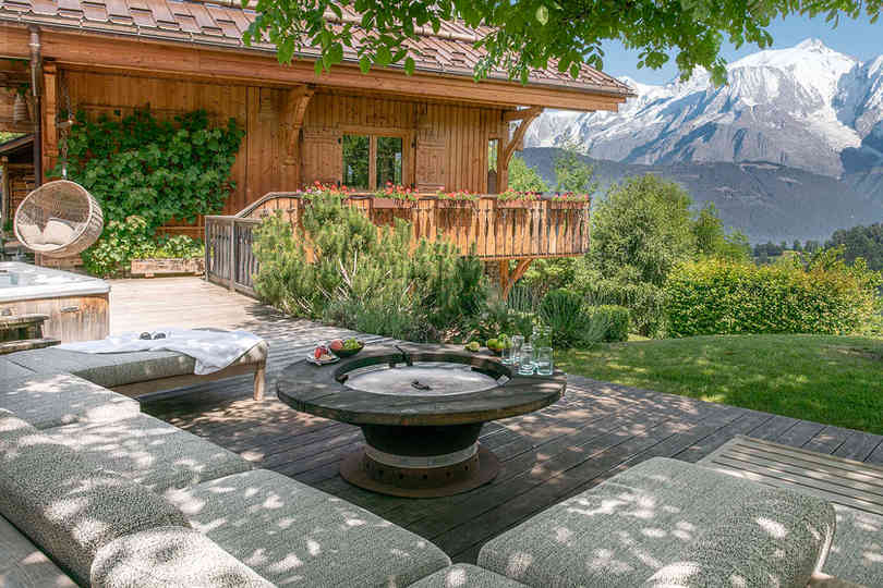An elegant fabric garden set in the garden of a summer chalet, set against the backdrop of snow-capped mountains near Megève.