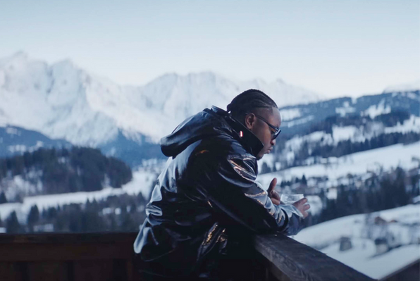 Landy, accoudé au balcon d'un chalet de montagne lors de son clip "la Grinta"