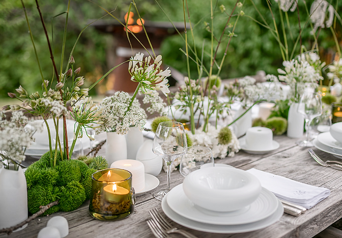 Élégante table d'été dans un jardin avec un brasero en arrière plan.