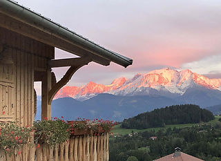 Le Mont Blanc rose pendant un alpenglow. AU premier plan le balcon dd'un chalet avec des jardinières remplies de géranium à la fin de l'été.