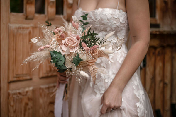 Bouquet tenu par une jeune mariée devant la porte d'un chalet de avoi