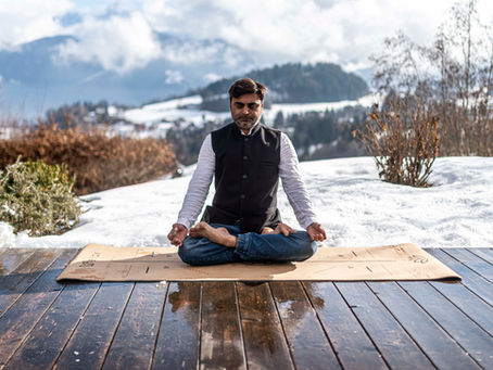 Sur une terrasse enneigée un homme assis en lotus pratique la méditation face au Mont-Blanc