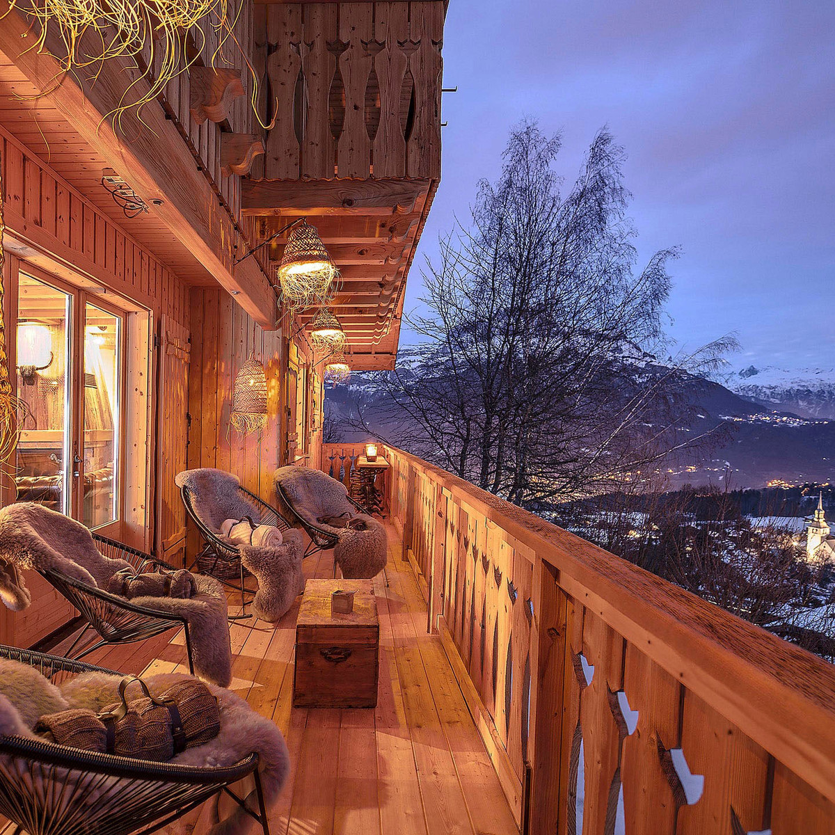 Balcon de chaet au crépuscule avec vue sur les montagnes enneigées et l'église du village de Cordon