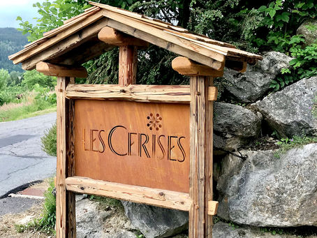 Enseigne en acier Corten et vieux bois indiquant le parking du Chalet & Spa les Cerises 