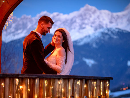 Un couple de jeune mariés au crépuscule sur le balcon d'un chalet en hiver avec le Mont-Blanc en arrière-plan
